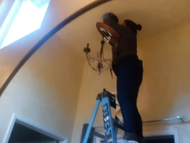 Electrician installing a chandelier in a Lake Worth Beach residence
